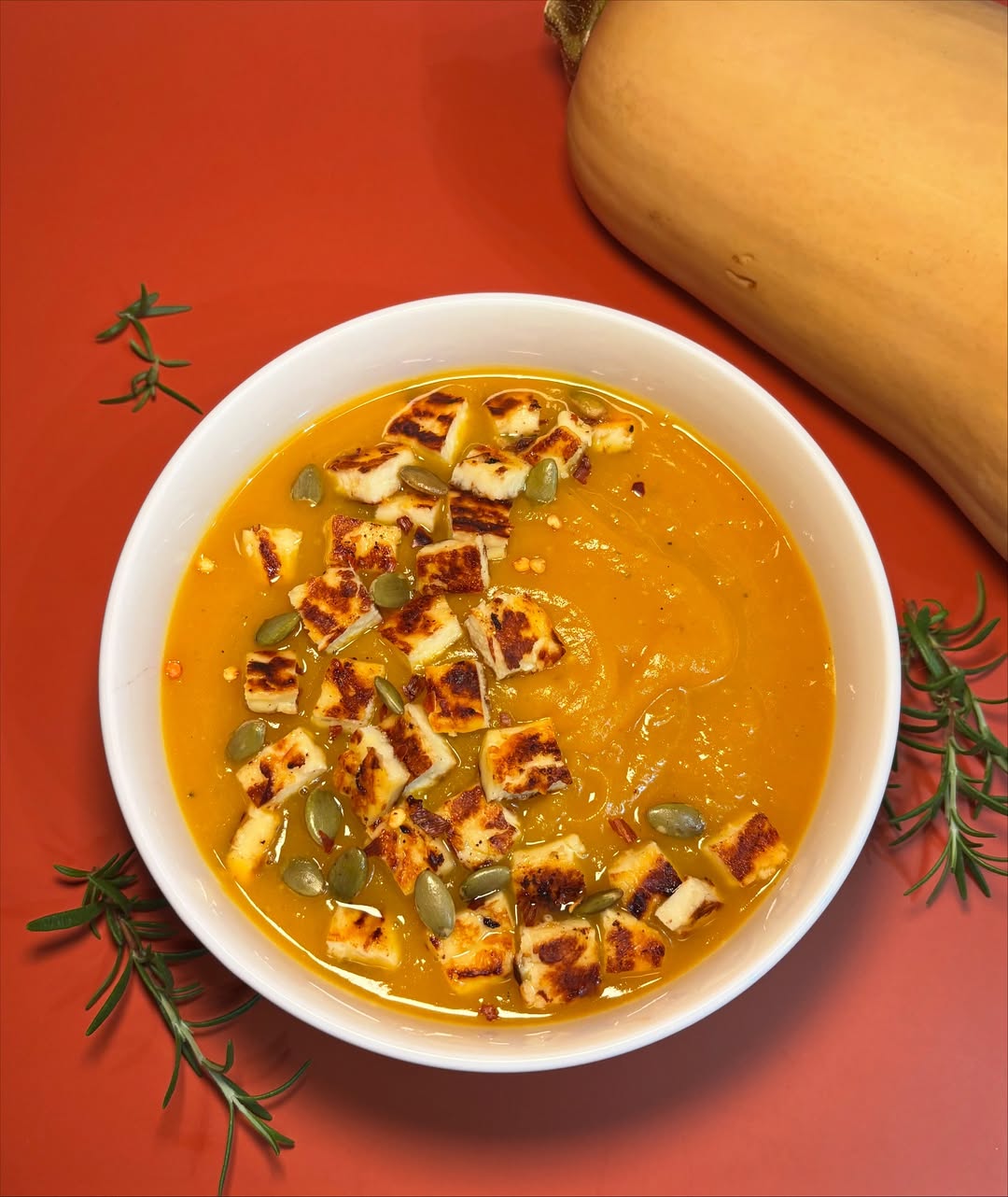 Creamy butternut squash soup topped with grilled halloumi and a drizzle of rosemary infused brow