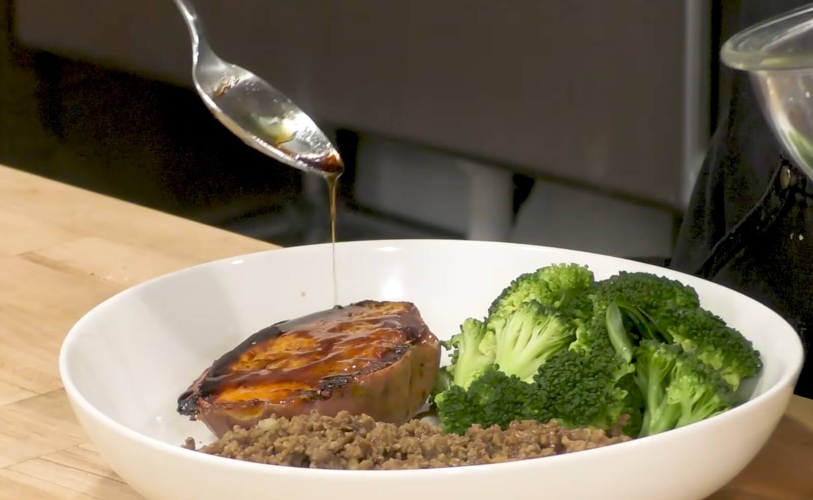 Adding sauce to the ground beef and sweet potato bowl