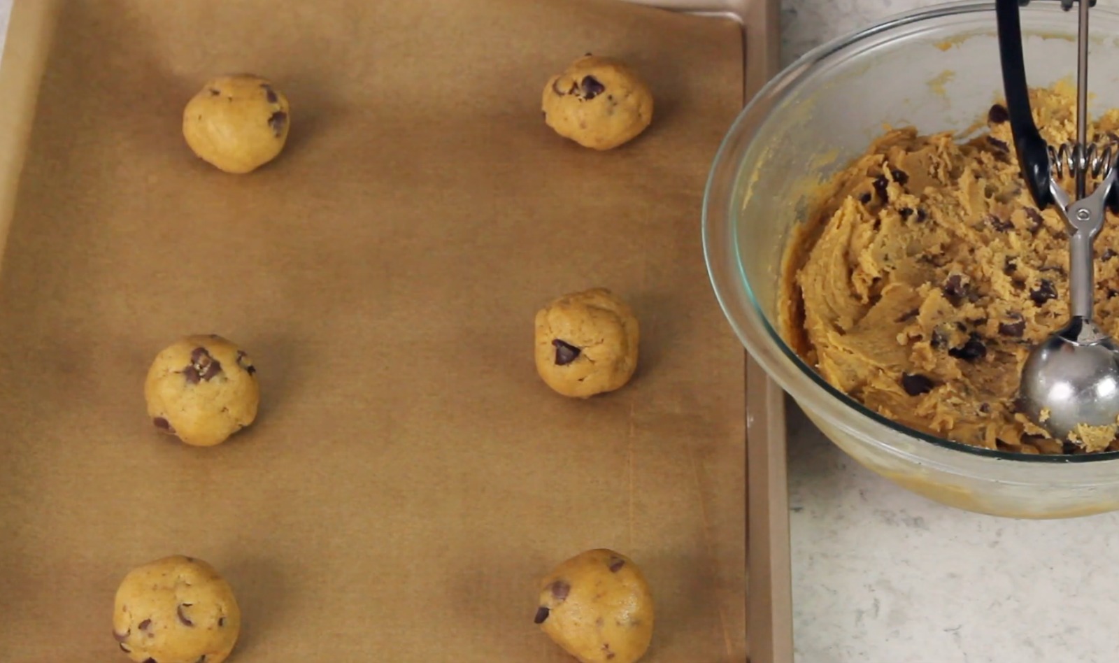 Rounded cookie dough portions on baking sheet
